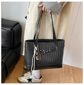 Close-up of black woven leather tote bag featuring silver eyelets and intricate texture