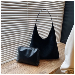 Detail of black matte tote bag set with matching smooth leather zipper pouch on a windowsill