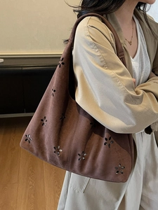 Brown suede tote bag with laser-cut floral pattern shown on shoulder by female model
