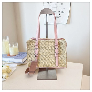 Detail of a woven straw tote with pink leather trim and a silver metallic buckle