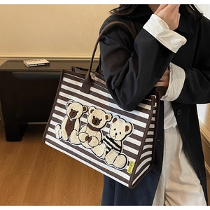 Détail du sac cabas en toile rayée avec écussons d'ours en peluche 3D et anses brunes