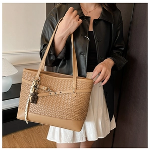 Close-up of tan woven tote bag with intricate leather texture and stylish pendant detail
