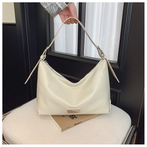 Close-up of cream white leather shoulder bag with metallic logo and adjustable strap