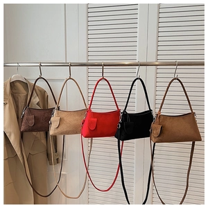 Detail of minimalist faux suede shoulder bags in five colors displayed on a rack