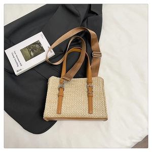 Detail of woven straw shoulder bag with brown leather straps on minimalist background