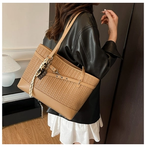 Detail of caramel brown woven tote bag with rope tassel and metal grommet strap