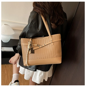 Detail of woven texture on camel tote bag with decorative strap and tassel accent