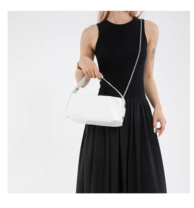Detail shot of the white bucket bag featuring a smooth PU leather finish and a metal chain