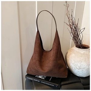 Detail of vintage brown suede hobo bag placed on books with minimalist interior decor