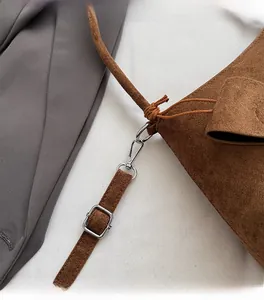 Close-up of silver metal hooks and adjustable strap on brown faux suede shoulder bag