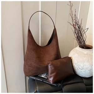 Close-up of deep brown frosted leather hobo bag and matching pouch on black bench