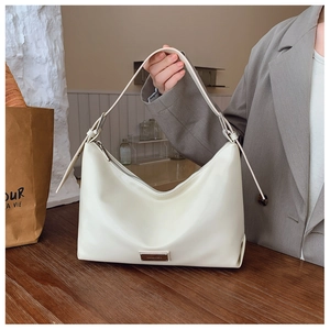 Detail showing creamy white hobo bag with metallic logo plate and silver buckle