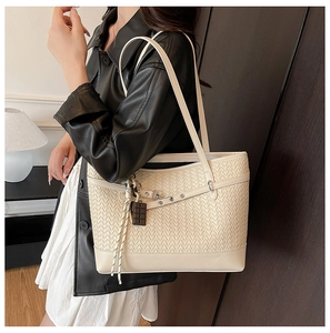Close-up of cream woven tote bag texture with chocolate charm and elegant side view