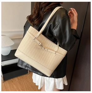 Detail of a beige woven tote bag showing fine texture, leather trim and metal lock clasp