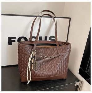 Detail of dark brown woven tote bag featuring grid texture and chocolate charm