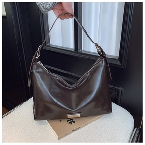 Detail of dark brown patent leather bag with glossy finish and silver buckle hardware