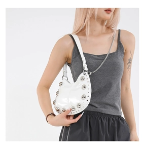 Close-up of a white crescent shoulder bag with large silver studs and metallic chain strap