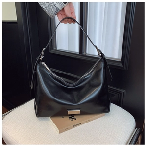 Detail of black glossy leather underarm bag with silver plaque and slim strap