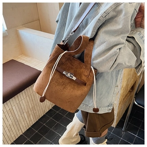Borsa a secchiello in camoscio marrone con cinturino in pelle e fibbia in metallo indossata