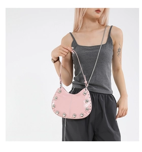 Détail du sac lune en cuir verni rose avec rivets argentés et bandoulière chaîne