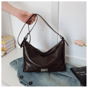 Detailed macro view of dark coffee glossy leather underarm bag with silver metal plaque