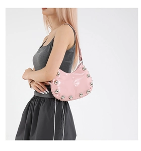 Détail du sac hobo en cuir verni rose avec de gros clous argentés et une bandoulière fine