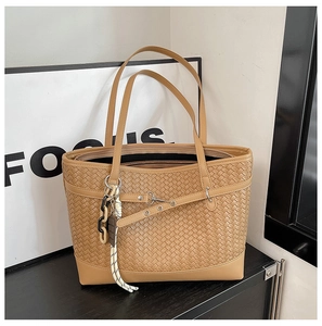 Detailed close-up of brown woven texture tote bag with metallic eyelet leather straps