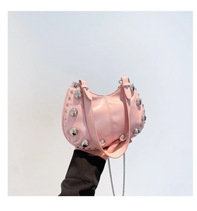 Détail du sac sous le bras en cuir rose avec de gros clous argentés et une chaîne