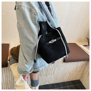 Detail of black suede bucket bag with white thick drawstring and silver metal twist lock