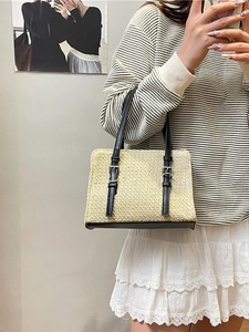Handmade beige woven straw tote bag with black leather base and straps for beach travel
