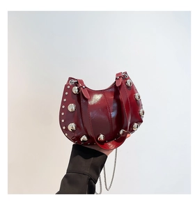 Détail du sac sous le bras en cuir verni bordeaux avec rivets argentés et bandoulière