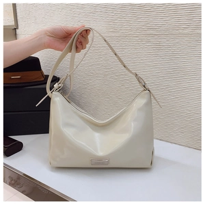 Detailed view of cream hobo bag with adjustable strap and polished metal logo plate