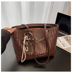 Detail of a brown woven tote bag with a chocolate charm on a minimalist desk