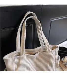 Détail du sac cabas en velours côtelé montrant la texture rayée et les anses solides