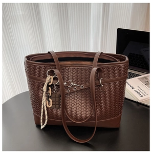 Detail of woven brown tote bag with metallic buckle and decorative chocolate charm