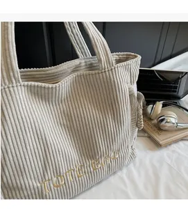 Gros plan détaillé d'un sac cabas en velours côtelé gris clair avec broderie dorée