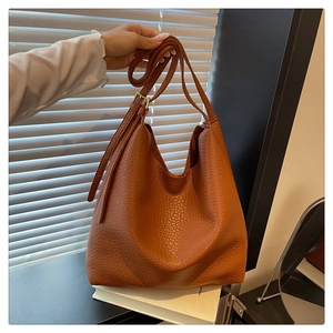 Detailed shot of brown lychee grain leather bucket bag with adjustable gold hardware