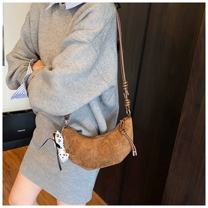 Dettaglio borsa croissant in pelle scamosciata marrone con tracolla annodata e foulard