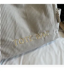 Gros plan du sac cabas en velours côtelé montrant la texture fine et la broderie