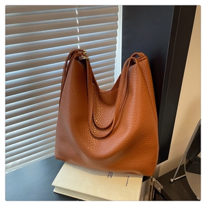 Macro shot of caramel brown tote bag showing high-quality lychee grain leather texture