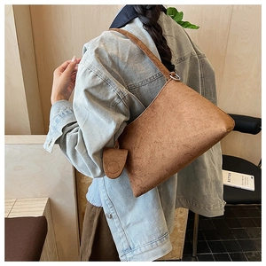 Detailed side view of a brown suede shoulder bag with a small matching round coin purse pouch