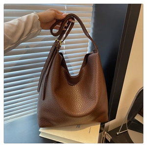 Close-up of brown textured leather hobo bag with adjustable strap and golden metal buckle