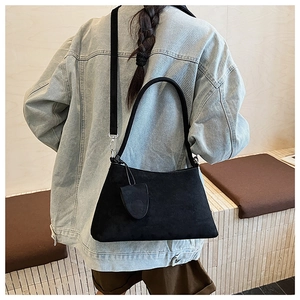 Detail of black suede crossbody bag showing matte texture and adjustable shoulder straps