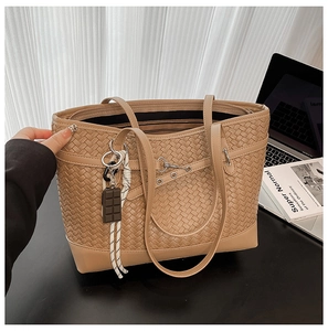 Detail of beige woven tote bag with chocolate charm and textured braided faux leather