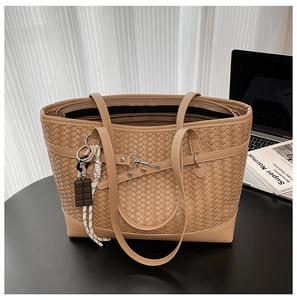 Detailed close-up of woven caramel tote bag with decorative chocolate-shaped charm and rope