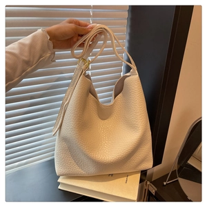 Detail of white lychee pattern leather bucket bag with adjustable strap and gold buckle