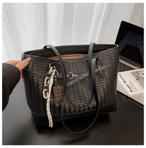 Detail of black woven tote bag with chocolate charm and cross-stitch texture