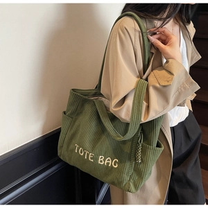 Gros plan sur le sac cabas en velours côtelé vert avec broderie blanche et texture
