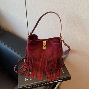 Close-up of burgundy suede bucket bag featuring long fringes and gold metal twist lock