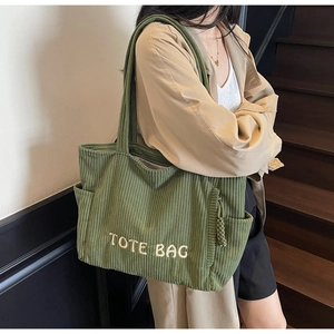 Détail du sac fourre-tout en velours côtelé vert montrant la texture et la poche latérale